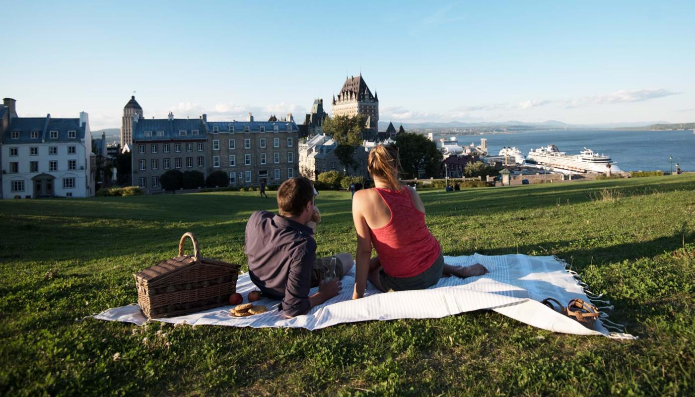 Pique-nique en couple près de la terrasse Pierre-Dugua-De Mons en admirant le Château Frontenac et le fleuve Saint-Laurent. 